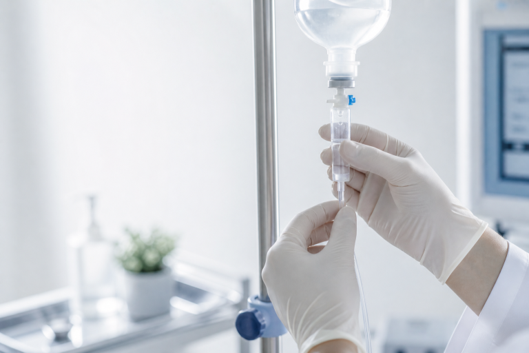Medizinische Nahaufnahme mit sterilen Handschuhen und Infusionssystem in sauberer klinischer Umgebung als Symbol für Sicherheit und Kontroll